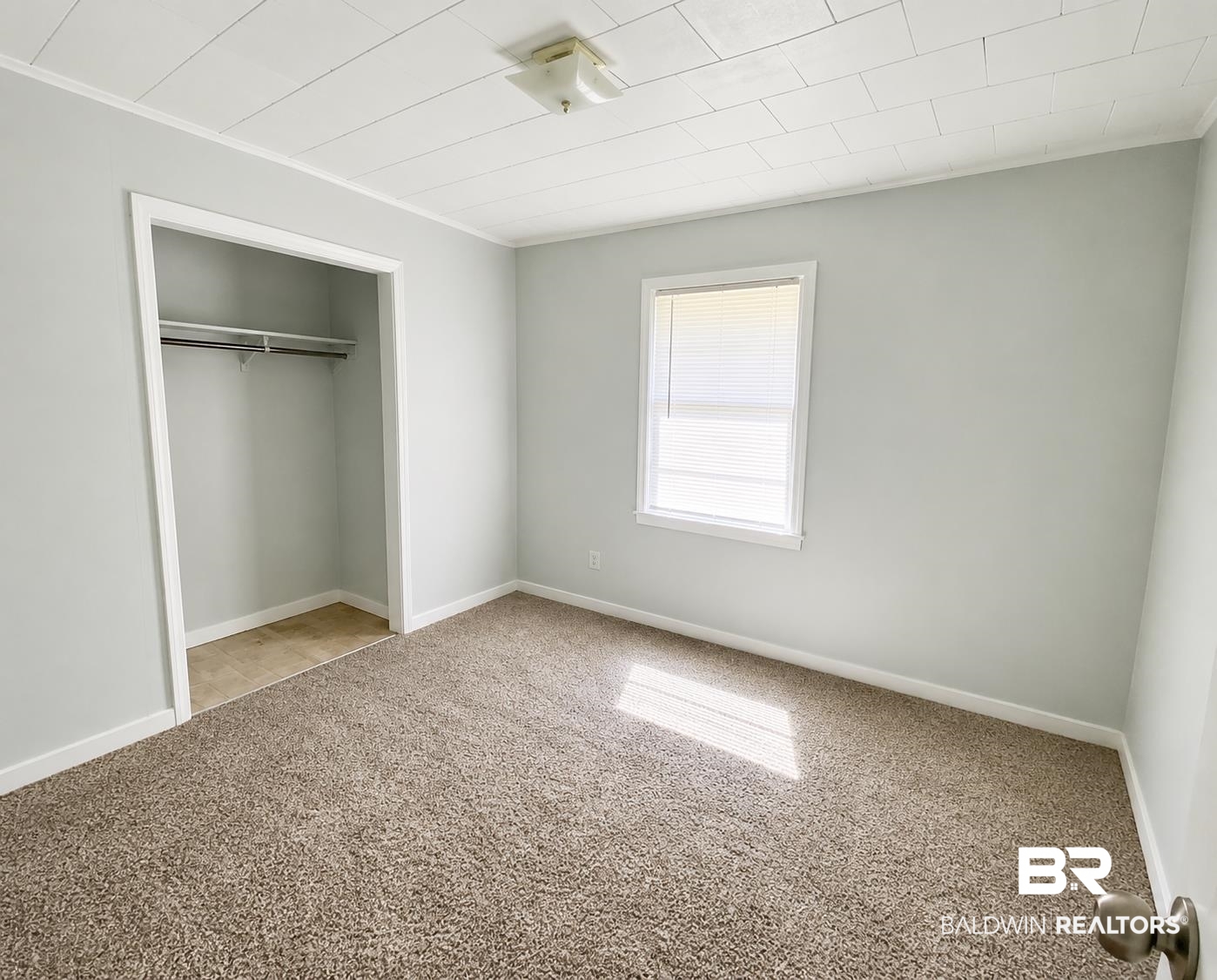 226 Elizabeth Street Evergreen, AL 36401 - Photo 27 of 35 Bedroom featuring neutral gray wall paint, brown textured carpet, a window with white blinds, and a closet with a hanging rod and tan flooring