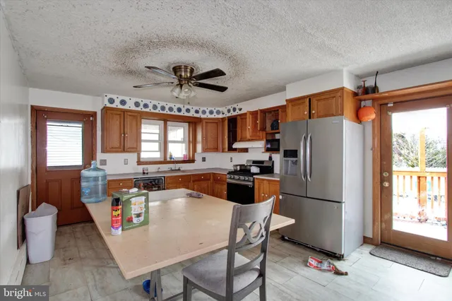 a large kitchen with a table chairs refrigerator and window