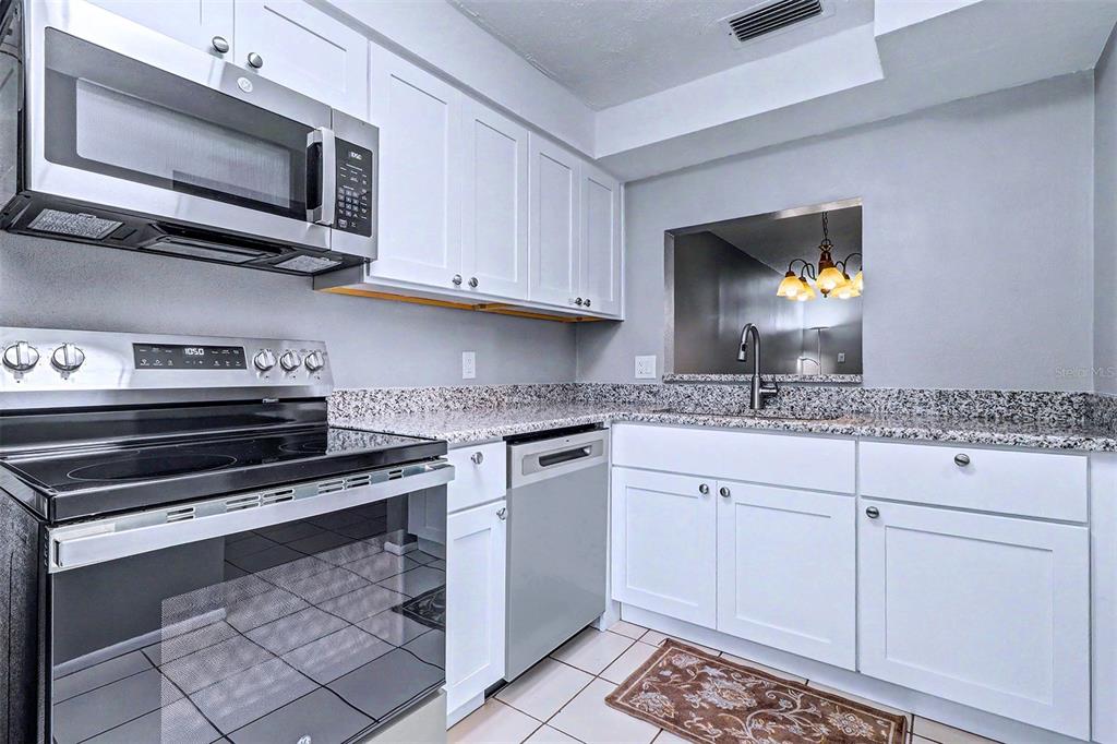 3661 Trophy Boulevard, Unit 3661 New Port Richey, FL 34655 - Photo 2 of 25 a kitchen with granite countertop cabinets stainless steel appliances and a sink