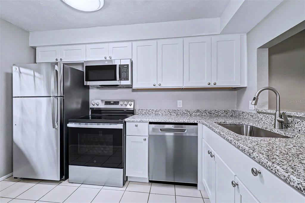 3661 Trophy Boulevard, Unit 3661 New Port Richey, FL 34655 - Photo 3 of 25 a kitchen with granite countertop a sink stove and refrigerator