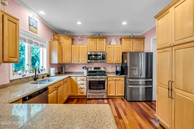a kitchen with stainless steel appliances granite countertop a refrigerator a sink dishwasher a stove and white countertops with wooden floor