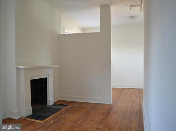 1018 North Charles Street, Unit R7 Baltimore, MD 21201 - Photo 6 of 13 a view of an empty room with wooden floor and a fireplace