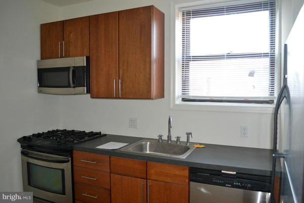 1018 North Charles Street, Unit R7 Baltimore, MD 21201 - Photo 8 of 13 a kitchen with granite countertop a sink stove and microwave