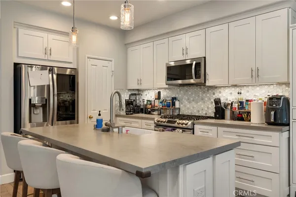 a kitchen with stainless steel appliances granite countertop a sink a stove and a refrigerator with wooden floor