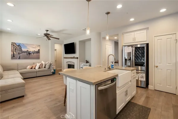 a large white kitchen with a stove a sink dishwasher and a refrigerator with wooden floor