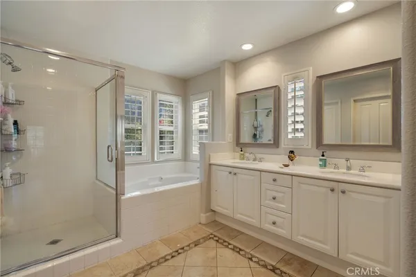 a bathroom with a double vanity sink a mirror a bathtub and next to a window