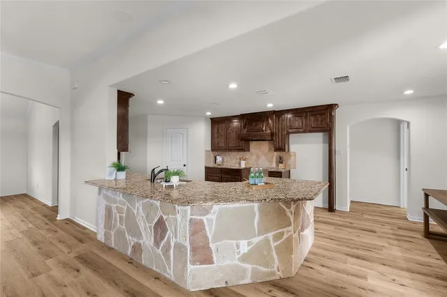 a large kitchen with stainless steel appliances granite countertop a lot of counter space and wooden floor