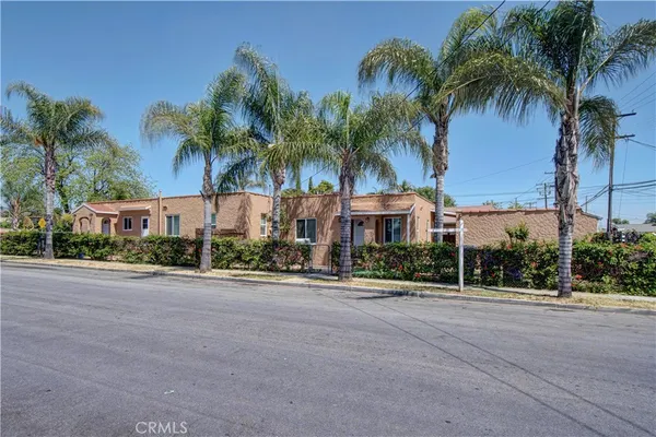 a front view of multiple houses with palm trees