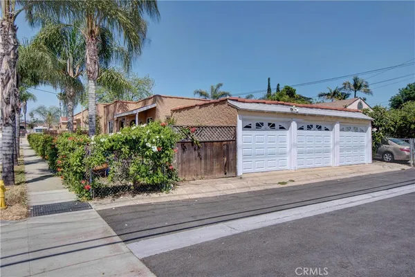 front view of house with a yard and palm trees