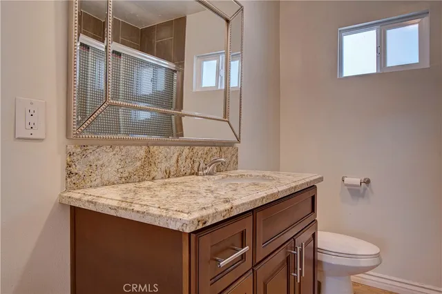 a bathroom with a granite countertop sink and a toilet