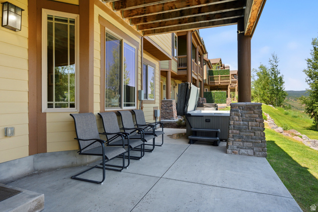 3148 Lower Saddleback Road Park City, UT 84098 - Photo 54 of 67 Covered concrete patio featuring a hot tub, stone-clad structural columns, and a landscaped grassy hillside