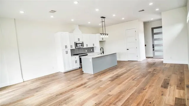 a large kitchen with stainless steel appliances kitchen island a large counter top and a stove top oven