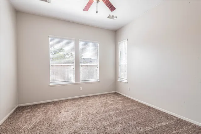 an empty room with a ceiling fan and a window