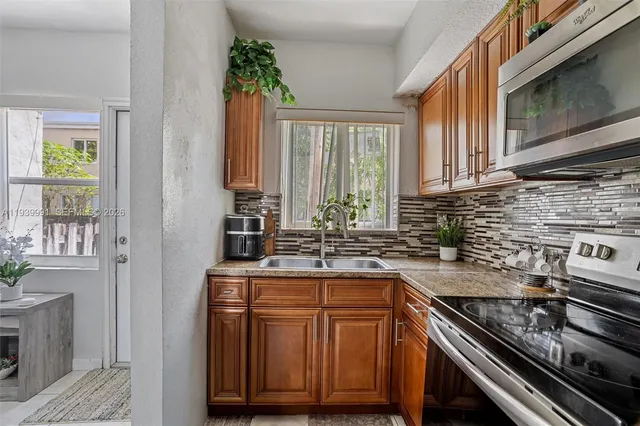 a kitchen with stainless steel appliances granite countertop a stove a sink and a microwave