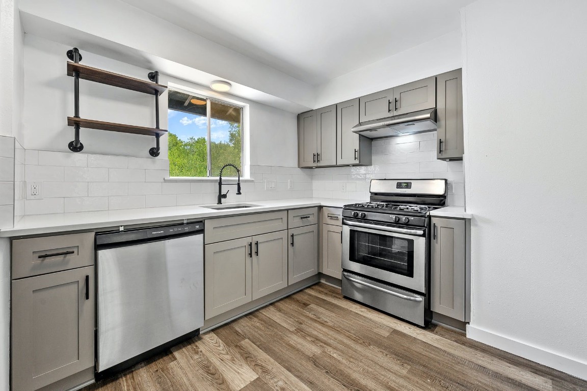 a kitchen with stainless steel appliances a stove and white cabinets