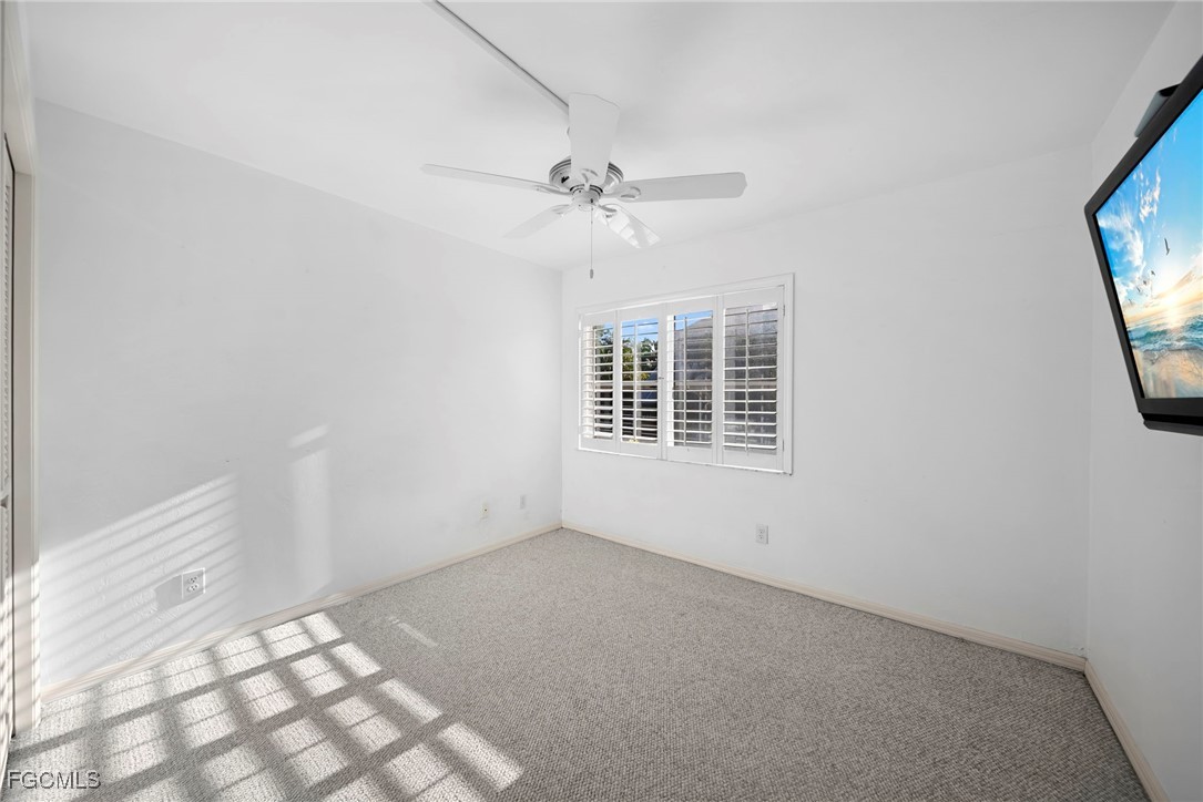 3052 Kings Lake Boulevard, Unit 7554 Naples, FL 34112 - Photo 24 of 32 an empty room with windows and fan