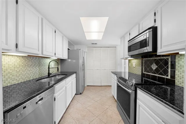 a kitchen with granite countertop a sink stainless steel appliances and cabinets