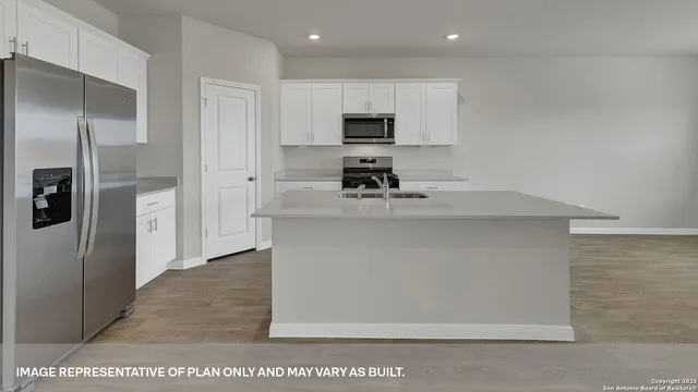 a kitchen with stainless steel appliances a refrigerator a sink and white cabinets