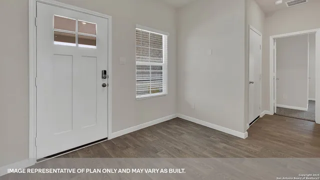 a view of an empty room with wooden floor and windows