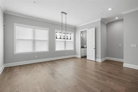 an empty room with wooden floor cabinet and windows