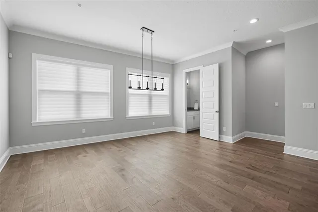 an empty room with wooden floor cabinet and windows