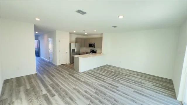 a view of kitchen and empty room with wooden floor