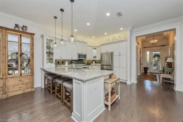 a large kitchen with stainless steel appliances kitchen island granite countertop a large kitchen island a stove a refrigerator a sink and a dining table with wooden floor