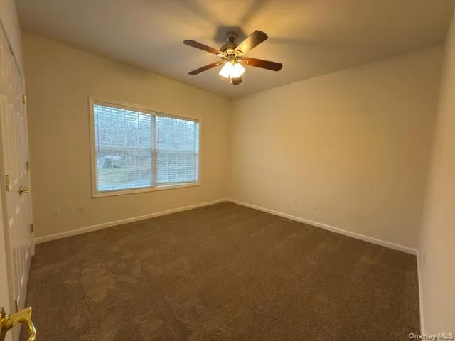 an empty room with a chandelier fan and windows