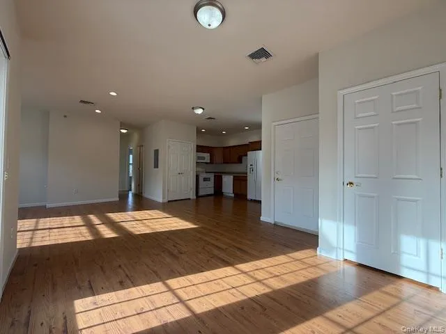 a view of an empty room and kitchen with furniture wooden floor and a window
