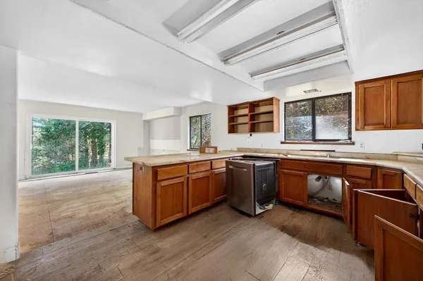 a large kitchen with stainless steel appliances granite countertop a sink and wooden cabinets