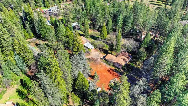 an aerial view of residential house with outdoor space and trees all around