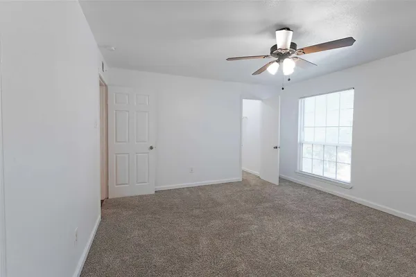 an empty room with windows and fan