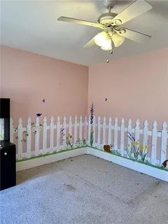 an empty room with windows fan and fireplace