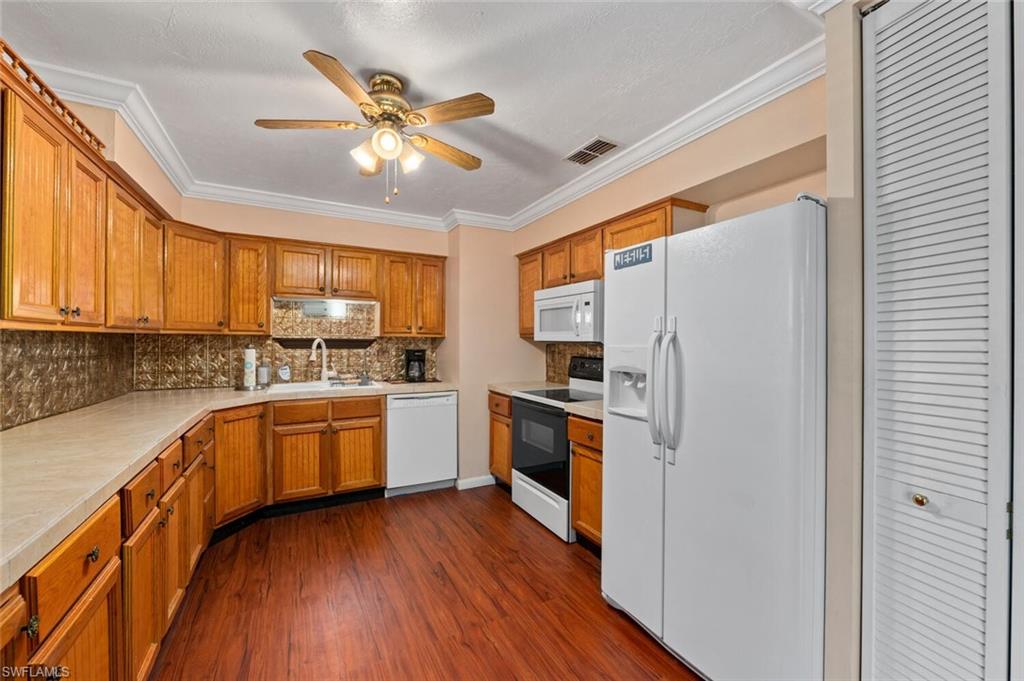 17520 Duquesne Road Fort Myers, FL 33967 - Photo 25 of 26 a kitchen with stainless steel appliances granite countertop a refrigerator a sink dishwasher a stove and white countertops with wooden floor