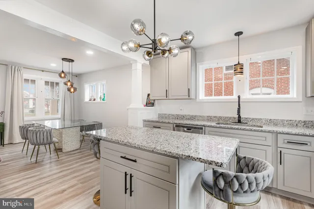 a kitchen with stainless steel appliances granite countertop a stove a sink and white cabinets with wooden floor