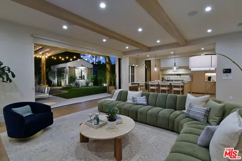 a kitchen with lots of white furniture and wooden floor