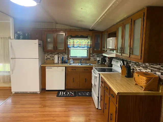 a kitchen with a sink a refrigerator and wooden floor