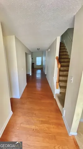 a view of a hallway with stairs and wooden floor