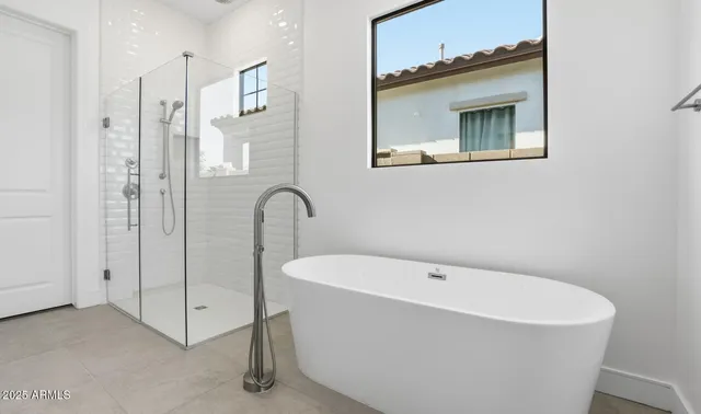 a bathroom with a tub sink double vanity granite tub shower and mirror
