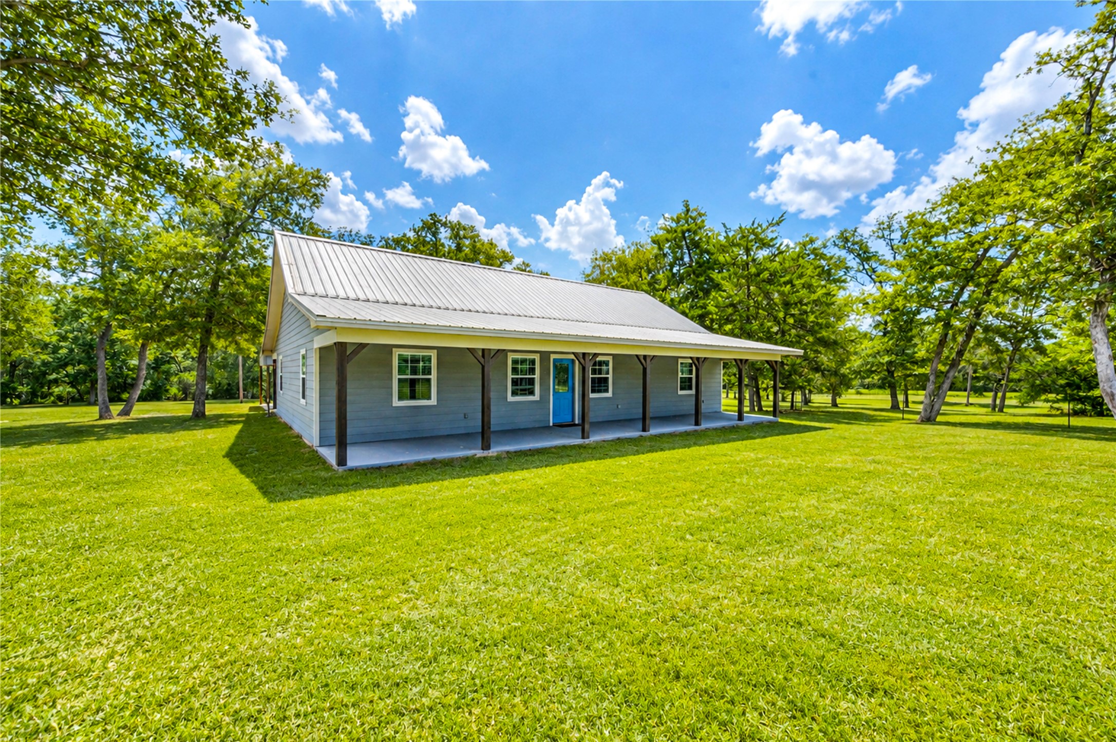 8805 Sun Oil Road Brenham, TX 77833 - Photo 9 of 50 Charming country home with a spacious front porch, surrounded by lush greenery and mature trees on a large, sunny lot.
