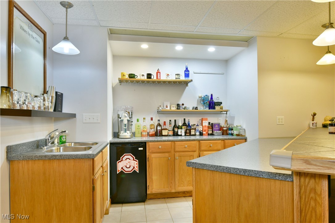 2907 Bushnell Campbell Road Fowler, OH 44418 - Photo 39 of 49 Indoor wet bar with dishwasher, light tile patterned floors, a paneled ceiling, and decorative light fixtures