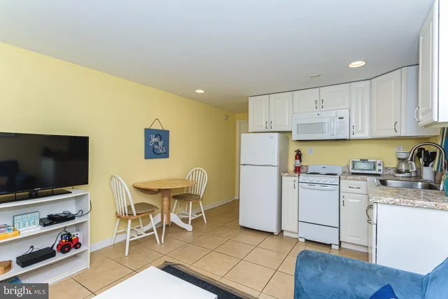 a kitchen with stainless steel appliances a stove a sink a refrigerator white cabinets and dining table with wooden floor