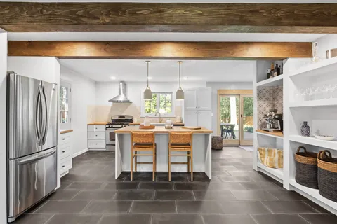 a dining area with stainless steel appliances kitchen island granite countertop dining table chairs and a large window