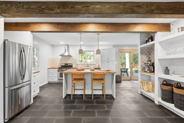 a dining area with stainless steel appliances kitchen island granite countertop dining table chairs and a large window