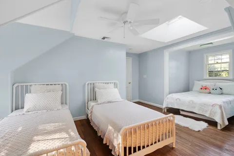 a bedroom with two beds and wooden floor
