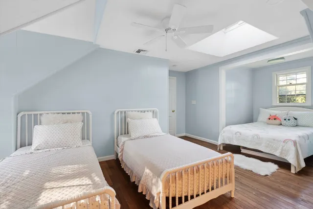 a bedroom with two beds and wooden floor