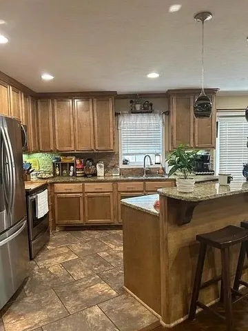 a kitchen with stainless steel appliances granite countertop a stove a sink a oven a dining table and chairs