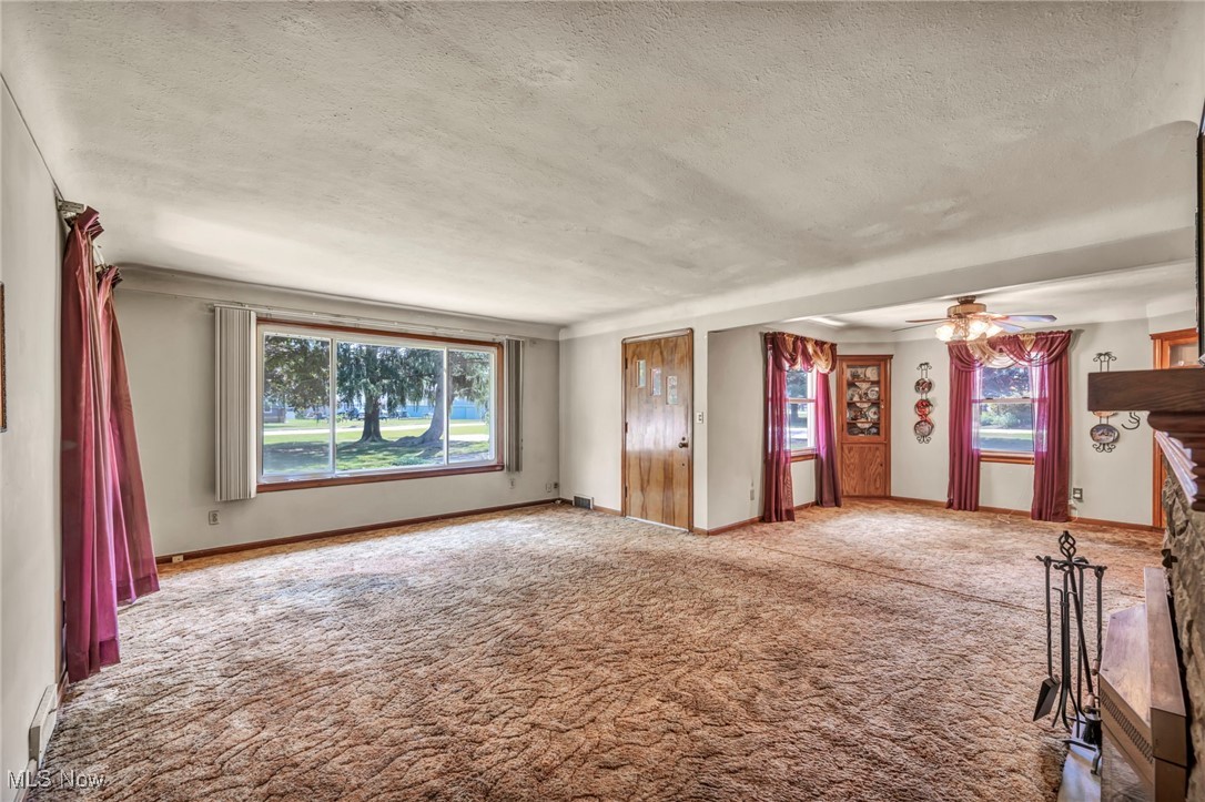 11858 Ridge Road North Royalton, OH 44133 - Photo 16 of 38 Carpeted empty room with a fireplace, a textured ceiling, and ceiling fan