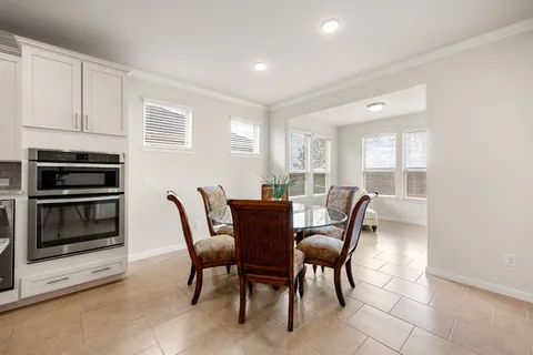 an empty room with chandelier fan and windows