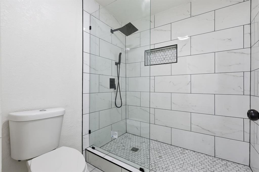 5940 Hunters View Lane Dallas, TX 75232 - Photo 12 of 24 Full bath with a tile shower and a textured wall